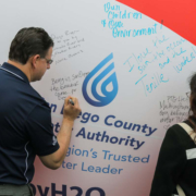 Attendees sign the "Brought To You By Water" symbolic beach ball, naming summer activities that rely on a safe and reliable water supply. Photo: Water Authority. Brought To You