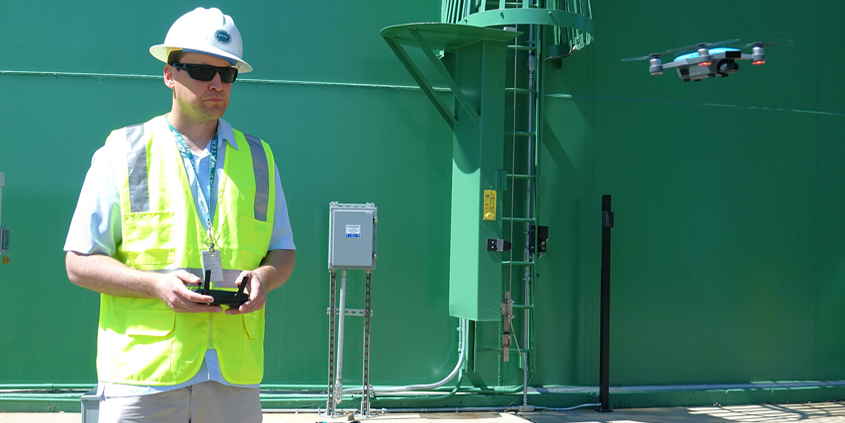 Alexander Schultz, Otay Water District geographic information systems technician, operates a drone in front of a district water storage tank. Photo: Otay Water District