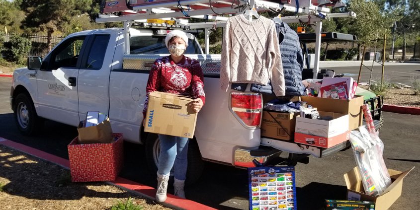 Teresa Chase helps load up donations from Olivenhain Municipal Water District employees. They are playing Santa Claus to a family of seven, a local senior, and a veteran in its annual adopt-a-family effort, and filled a truck bed with donations for the San Diego Humane Society. Photo: Olivenhain Municipal Water District